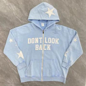 Light blue hoodie with star patterns and text on a gray floor